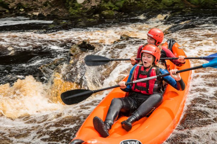 two girls kayaking on a river